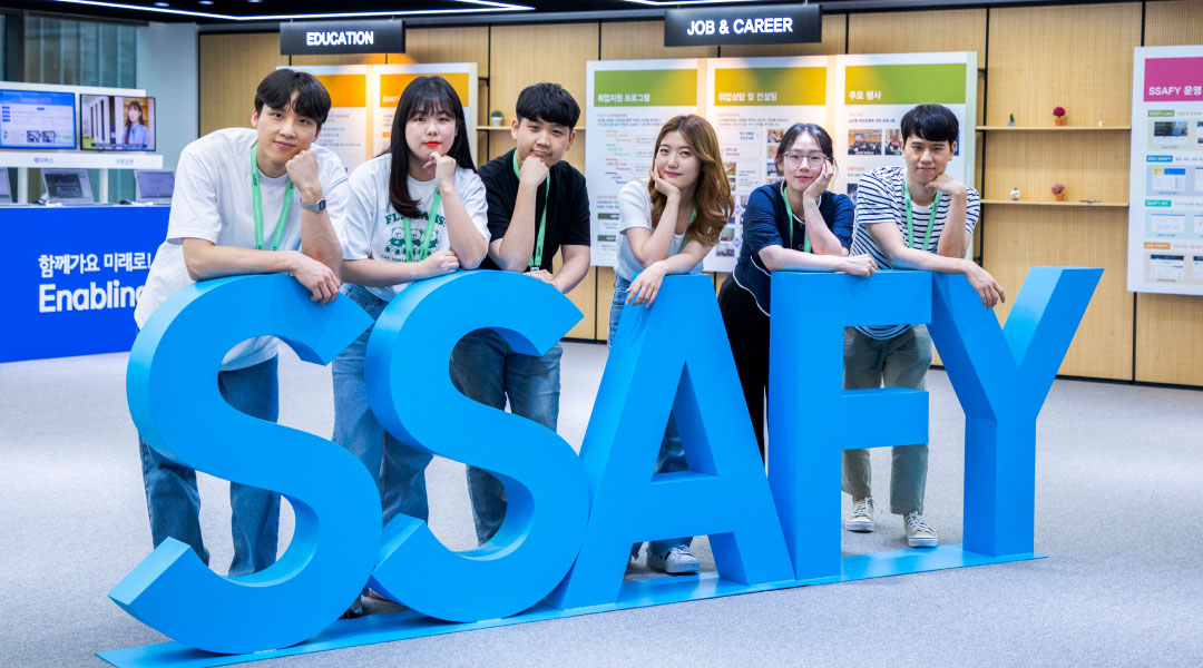 People taking a commemorative picture behind the SSAFY sculpture